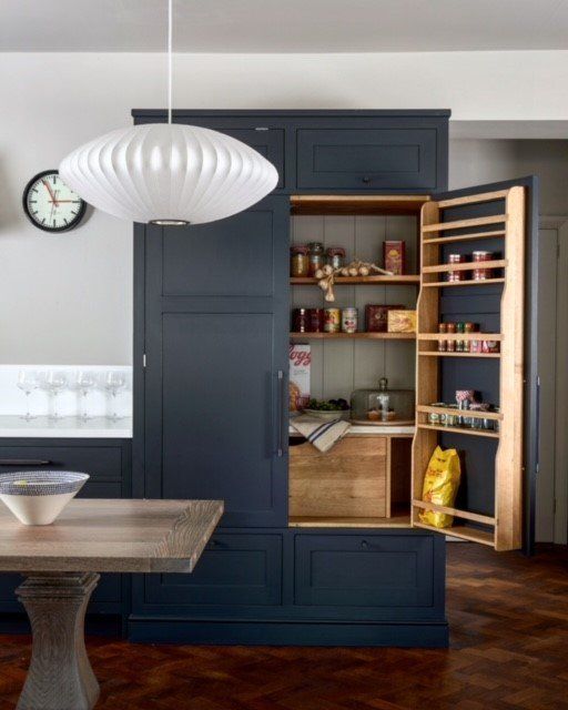 A tall navy hand-built larder cabinet by Stroud Furniture Makers with bun feet and an internal spice rack