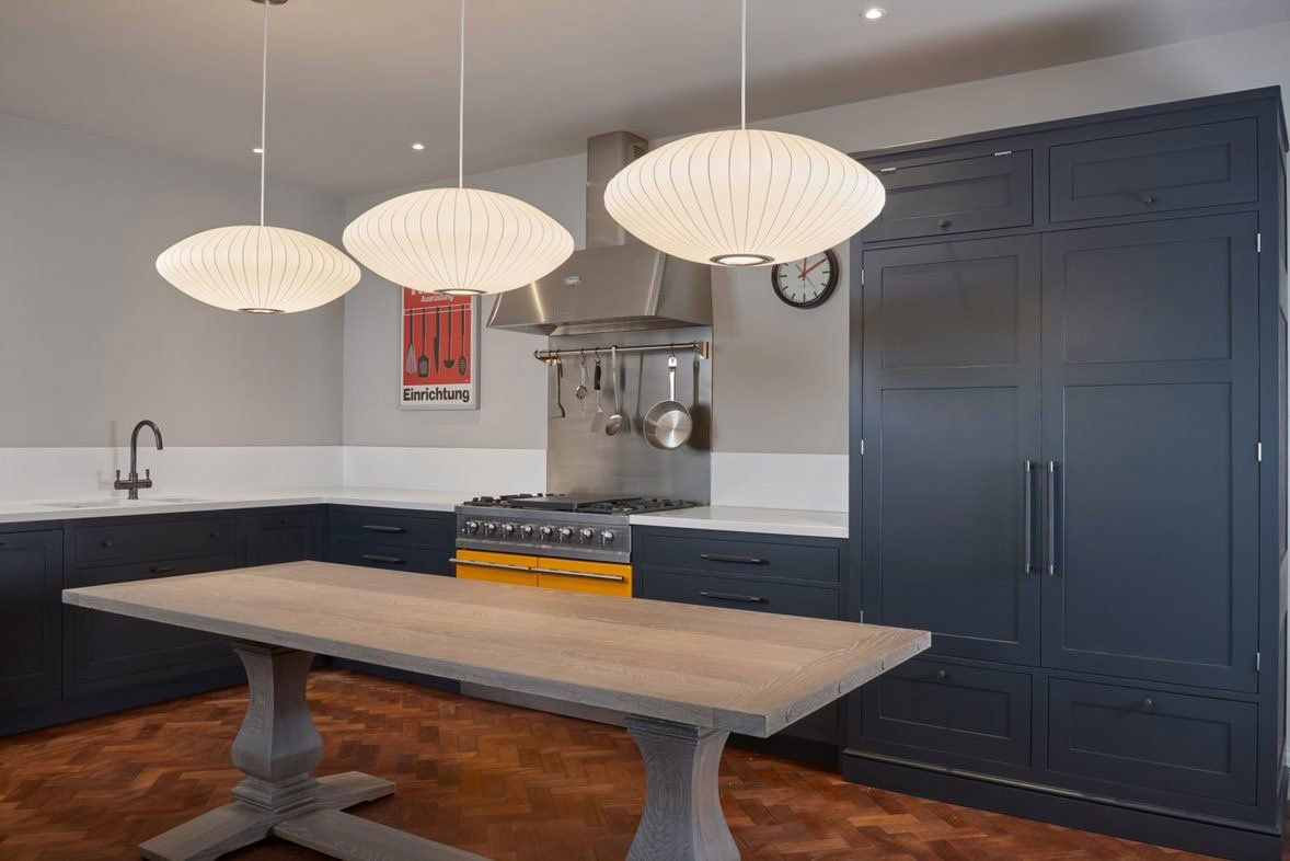 Deep-navy shaker cabinets, parquet, and a grey-oak refectory table for the family.