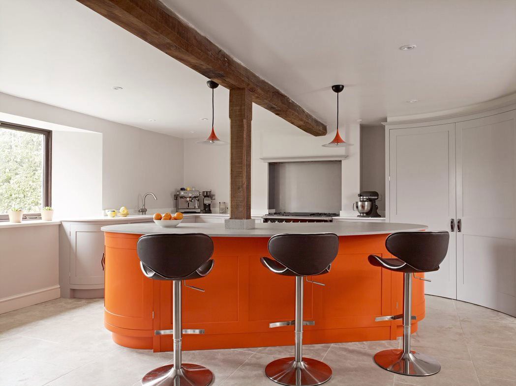 A curved island in burnt orange, built around the original oak beam.